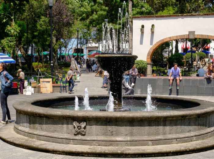 People enjoying a public square with a central fountain in Mexico City  