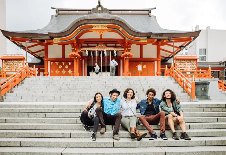 group of friendssitting on the steps of a temple
