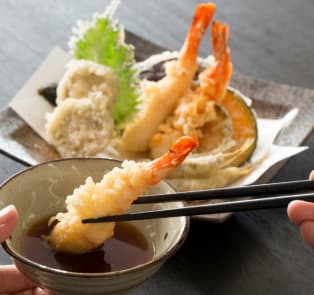 Tempura prawns been eaten with chopsticks