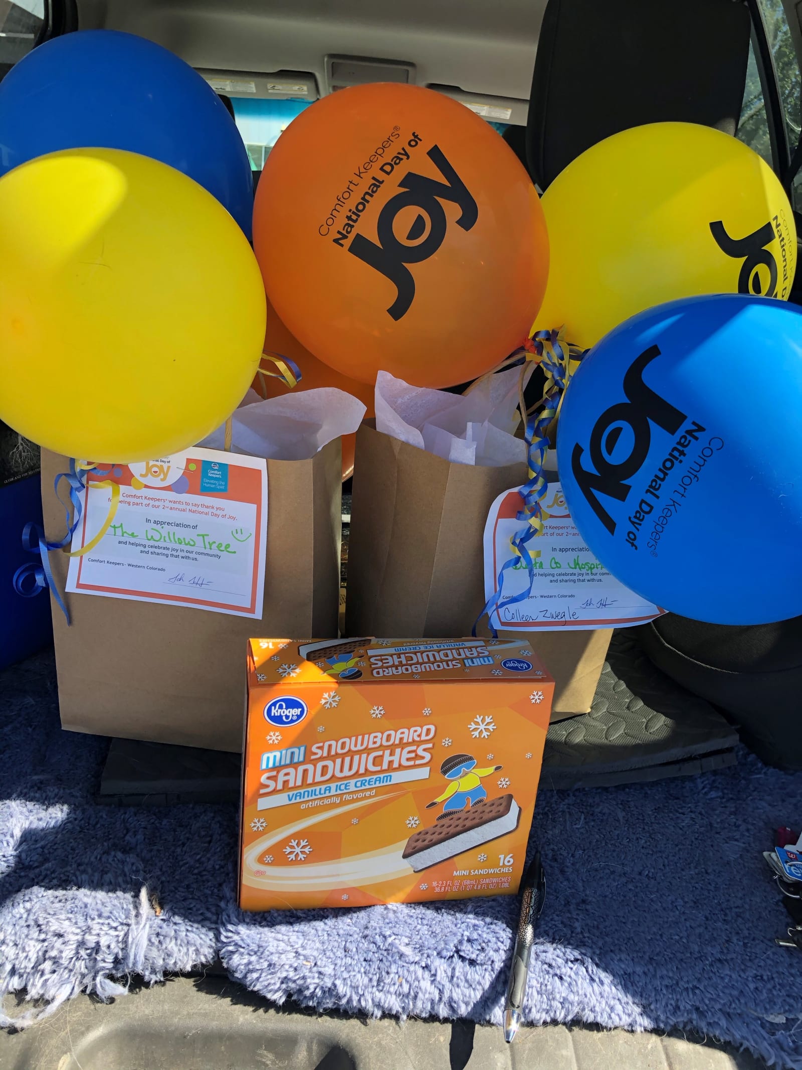 Boxes of gift bags and ice cream sandwiches loaded in a car with Day of Joy balloons