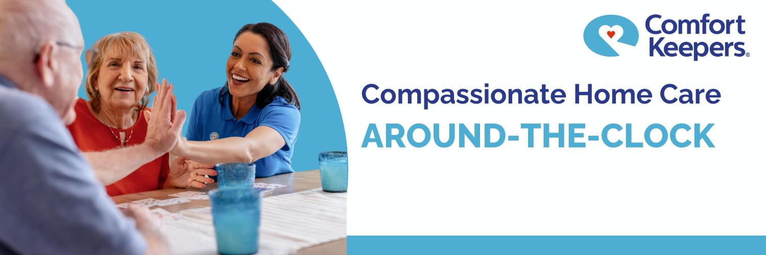 A caregiver sitting at a table with a senior couple, beside the words Compassionate Home Care Around-the-Clock