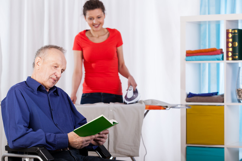 A respite care provider irons for a senior man in Snyder, TX