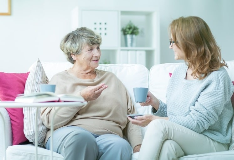 Adult home care provider and senior having coffee