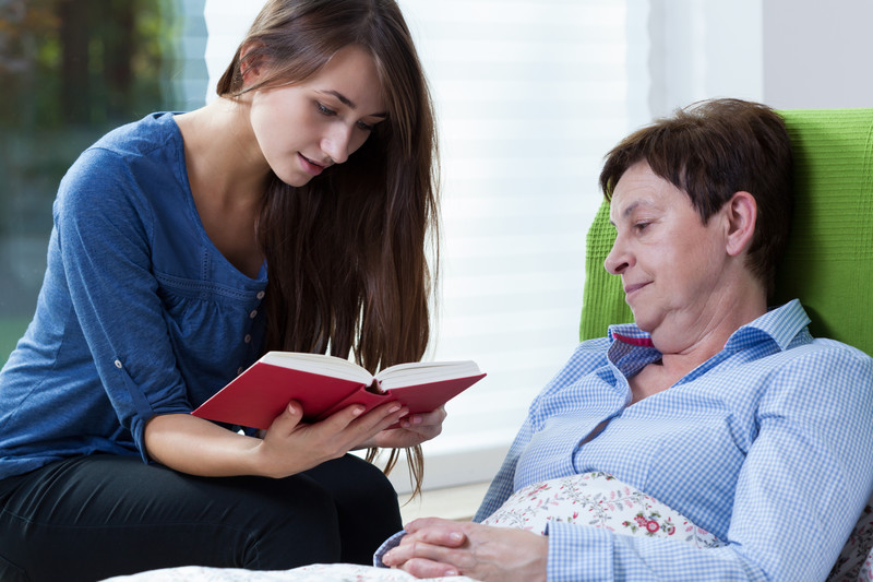 A geriatric home care provider reads to a senior woman in Kannapolis, NC