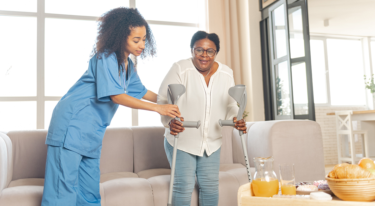 A caregiver helps an senior woman with her walker. Mobility assistance is one of the aspects of Transitioning Home Care provided by Comfort Keepers.