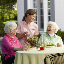 Caregiver serving food to two seniors. 