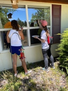 Two people painting on window