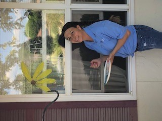 Caregiver smiling next to window with a sunflower painted on it