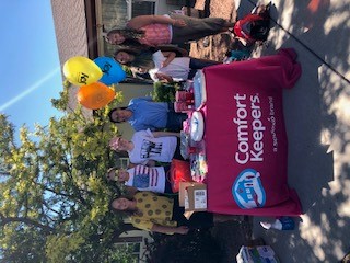 Photo of Comfort Keepers team standing behind their company table with balloons