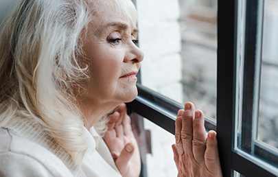 upset and isolated senior near window at home during quarantine