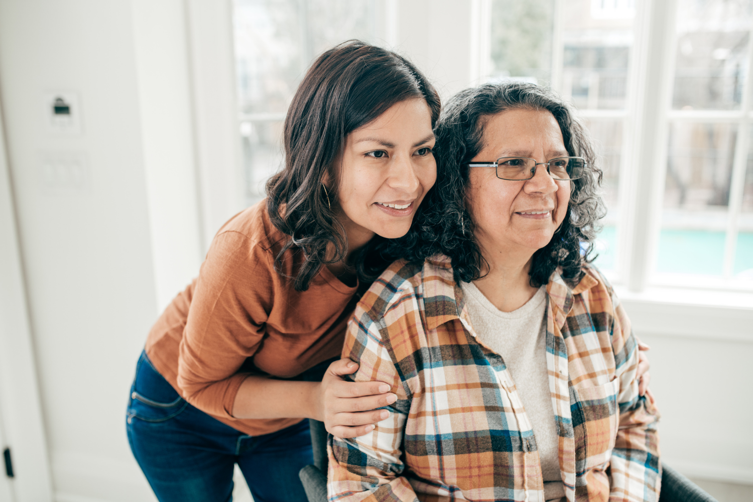 Daughter putting hands on shoulders of seated mother