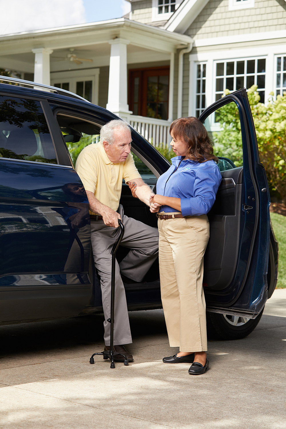 Comfort Keepers caregiver helping a senior male from the passenger seat of a van