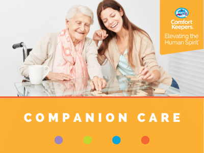 Comfort Keepers Home Care Graphic for Companion Care Services - shows a senior can caregiver playing dominos