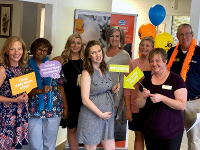 Comfort Keepers Team Holding Celebration Signs for National Day of Joy