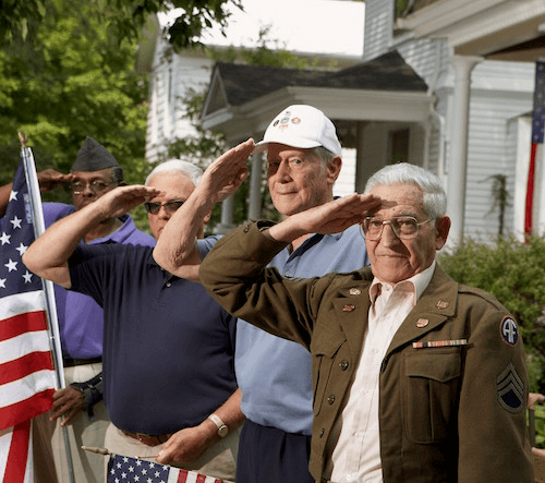 Four veterans saluting and holding the American Flag