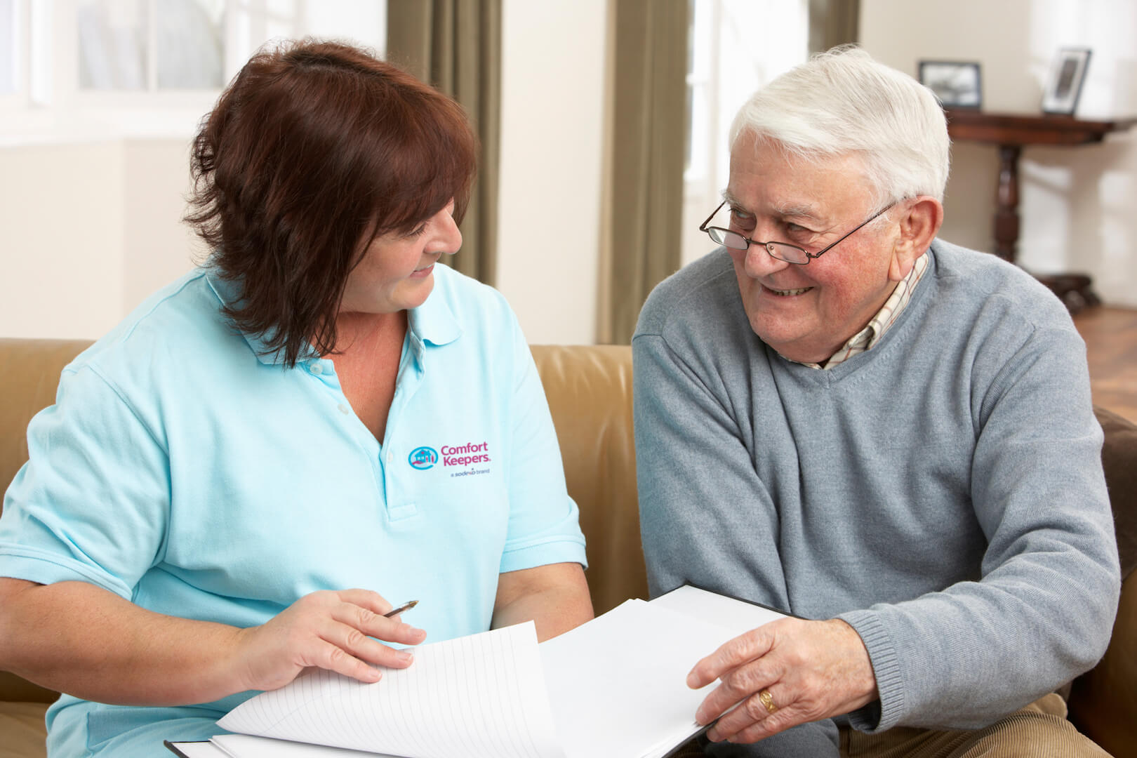 Photo of Comfort Keepers caregiver helping a senior go through documents