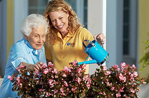 Caregiver Providing Senior Companionship Outside with Senior watering plants