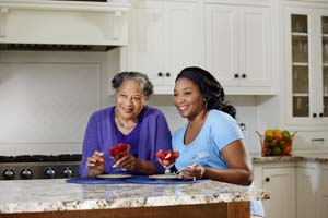 Comfort Keepers providing Home Care Baltimore MD and sharing dessert with senior in kitchen