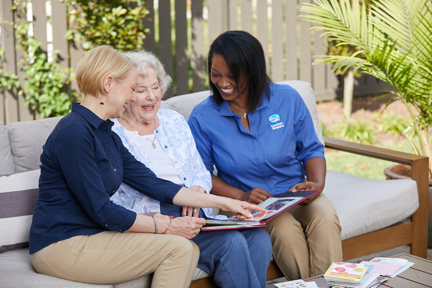 two caregivers looking at photo album with senior