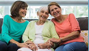 Senior with two daughters on sofa at home