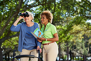 Senior and caregiver outside birdwatching in park