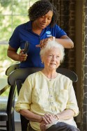 Caregiver grooming hospice seniors hair in her home