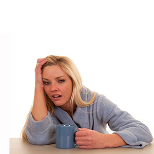 Tired Parsippany caregiver with cup of coffee leaning on table