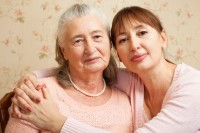 Senior woman who has dementia with her caregiver staring at camera