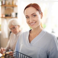 Smiling essex county caregiver with senior at kitchen table in background