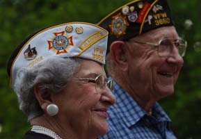 Two senior veterans in uniform standing outside and smiling