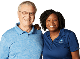 Caregiver and client stand side by side while looking into the camera and smiling