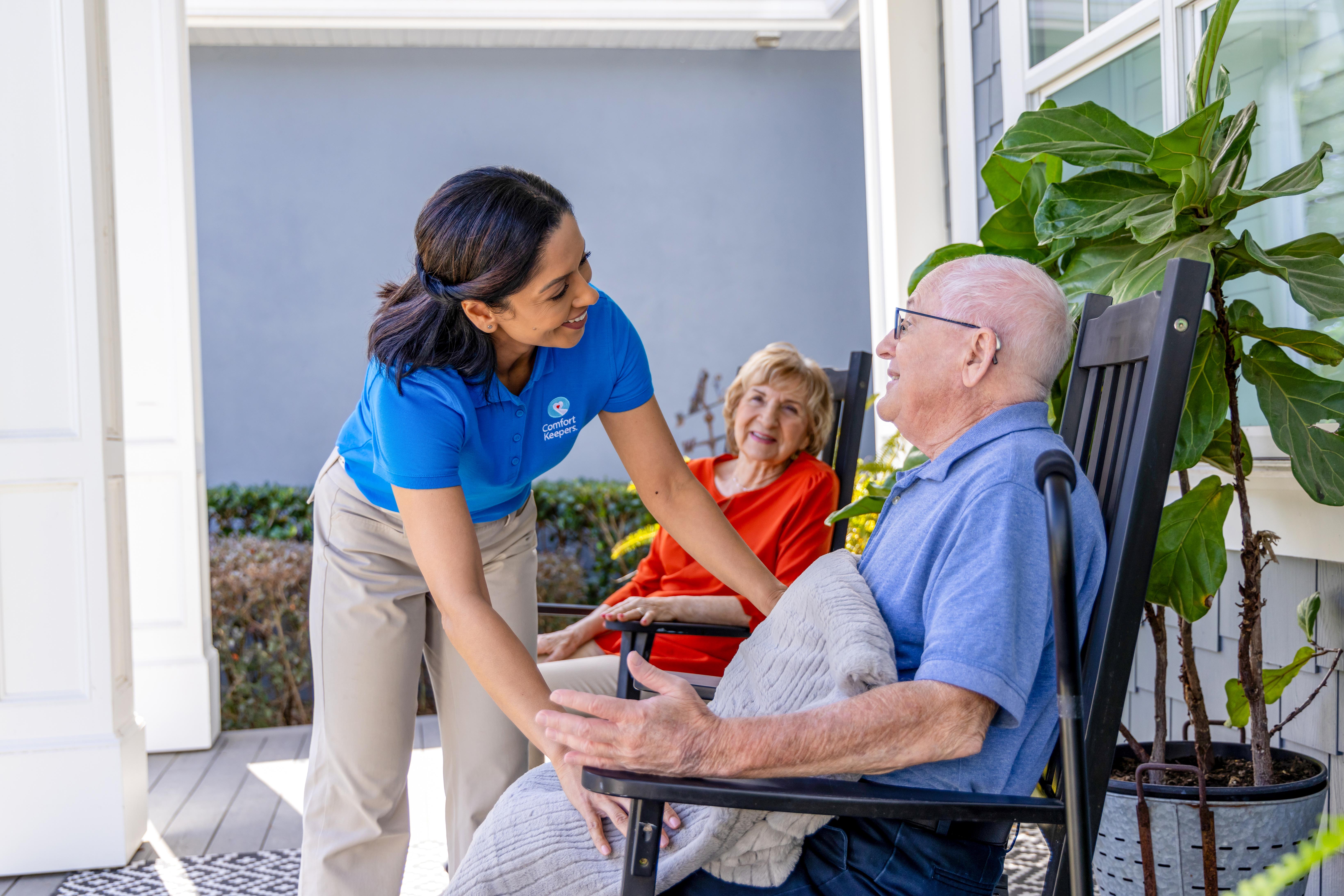 A Comfort Keepers caregiver provides memory care in Colorado Springs to an elderly man while his wife smiles about the specialized care he is getting.