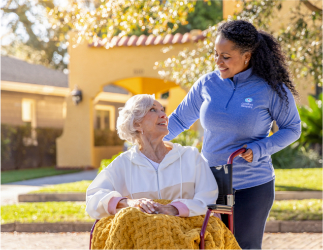 Caregiver pushing client in wheelchair while taking a stroll outside
