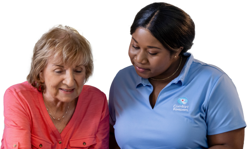 A caregiver helping their client both looking down at an object off screen.