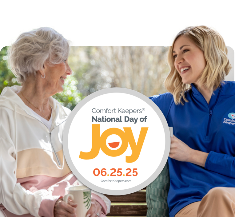 A caregiver and client sharing a warm conversation and laughing while sitting outside on a bench in a park.