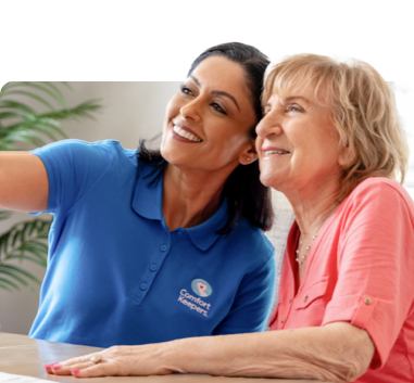 Caregiver and client smiling while posing for a selfie with a camera out of frame.