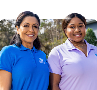 Two caregivers smiling warmly as they pose in their Comfort Keepers company polos.