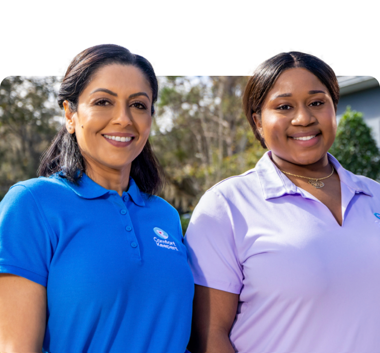 A caregiver helping their client bake cookies in a bright kitchen as they laugh together.