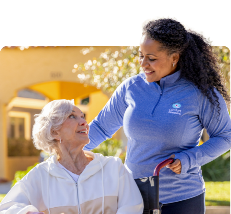 A caregiver helping their client bake cookies in a bright kitchen as they laugh together.