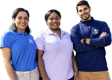 Three caregivers in their Comfort Keeper polos standing side by side and smiling in to the camera
