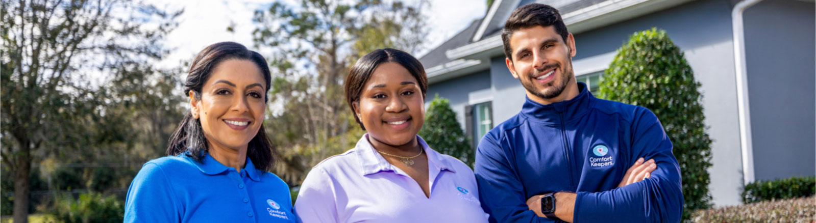 Three caregivers posing outside a home smiling warmly into the camera