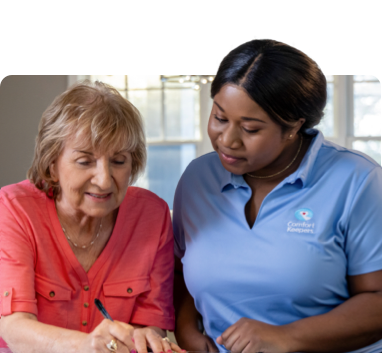 Caregiver helping assisting client while they write.