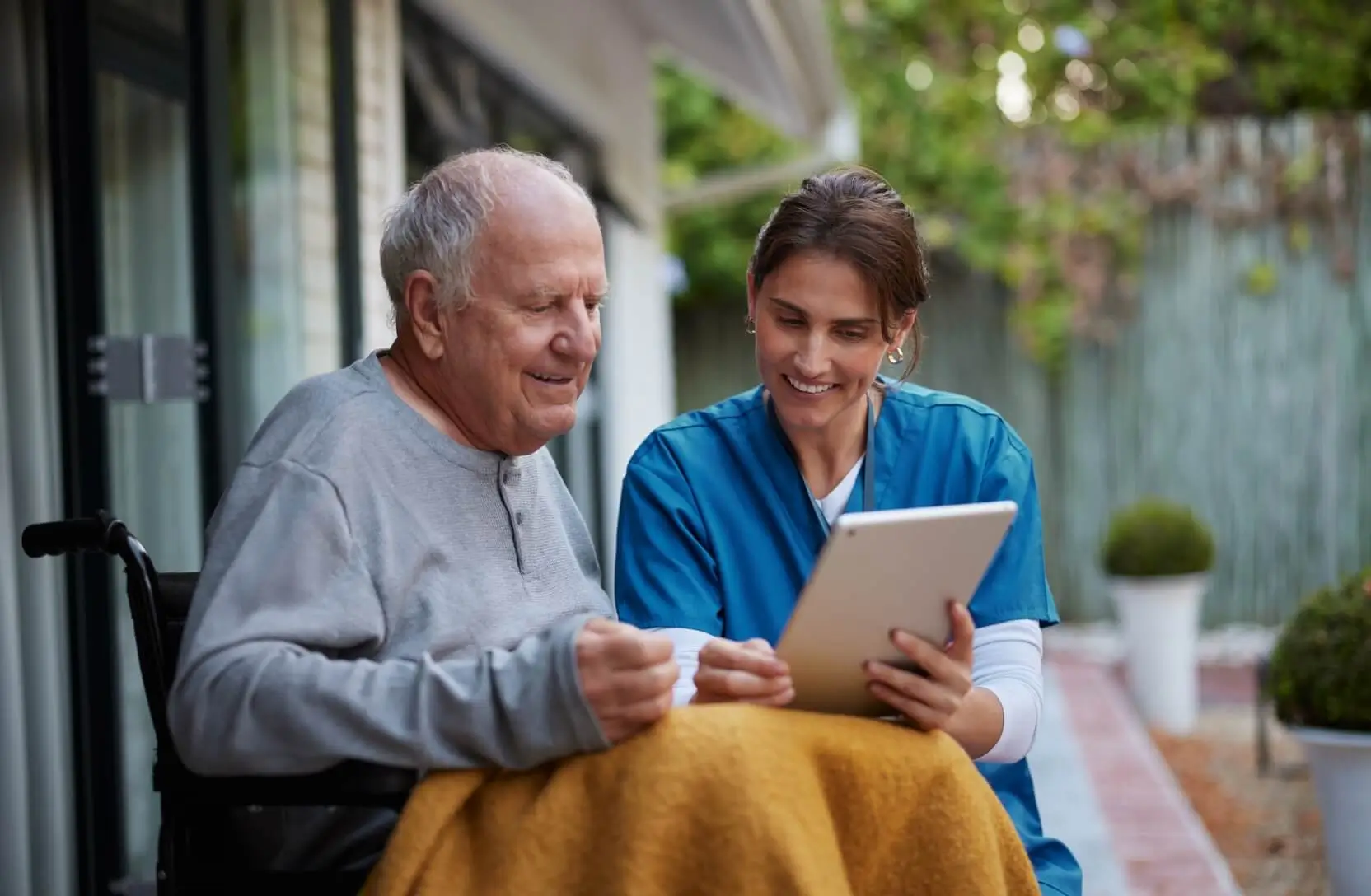 A nurse shows a tablet to an elderly man