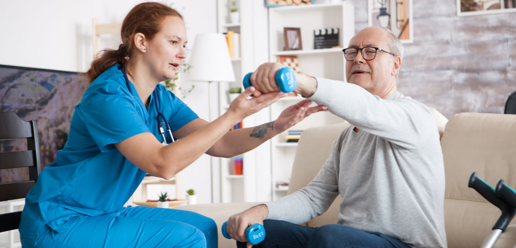 An in-home caregiver helps a senior man with mobility exercises.
