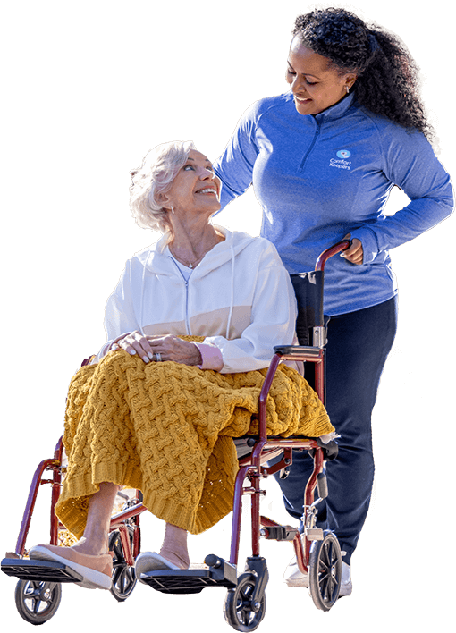 Caregiver pushing client in wheelchair while on an outdoor walk.