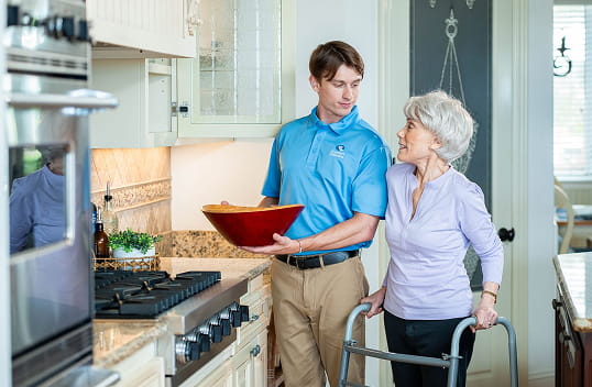 Caregiver walking client outside with walker