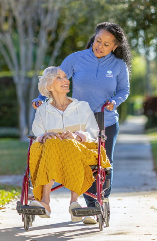 Caregiver walking client outside with walker