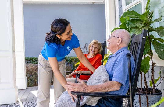 Caregiver helping client with a blanket on front porch
