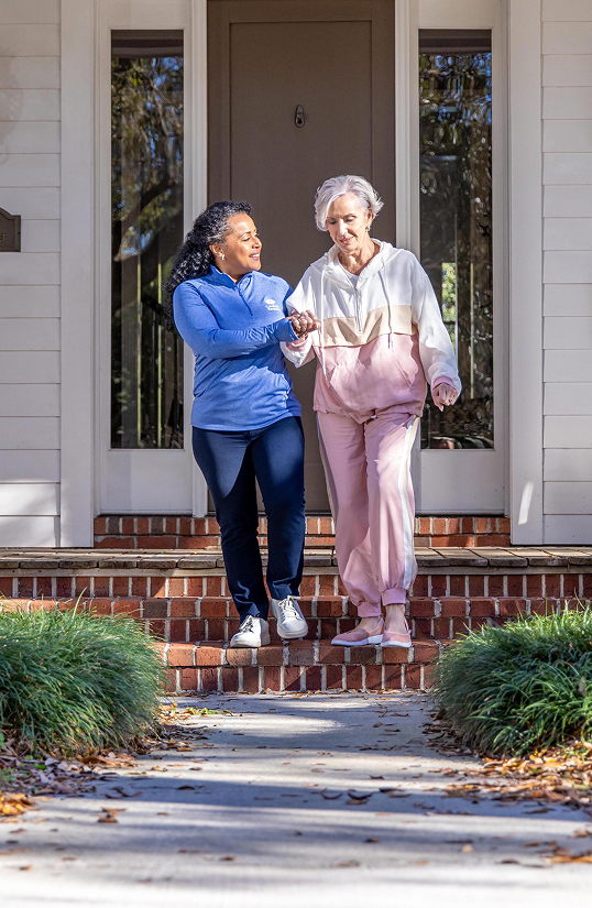 Caregiver walking client outside with walker