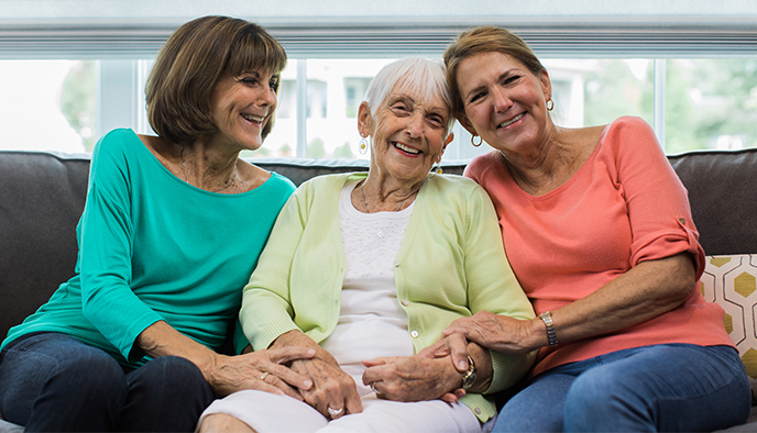 Smiling senior woman sitting with two family members at home in South Colorado Springs